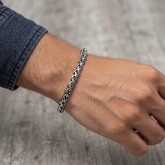 1792223926713 - Zanghi collection Close-up of a wrist wearing a chunky silver chain bracelet, with a denim sleeve visible nearby.