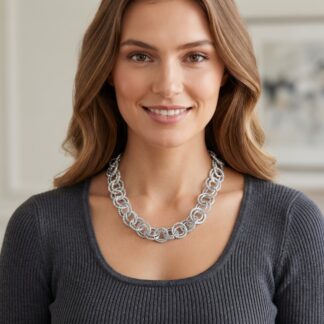 Close-up of a smiling woman wearing a chunky silver necklace and a dark gray ribbed sweater.