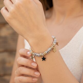 Close-up of a wrist wearing two-tone braided bracelets with gold star charms hanging from them.