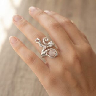 Close-up of a silver wire-wrapped ring with a round gemstone on the middle finger