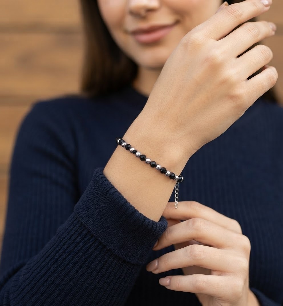 1791955157792 - Zanghi collection Close-up of a woman's wrist wearing a black and silver beaded bracelet with an adjustable chain, against a navy sweater sleeve.