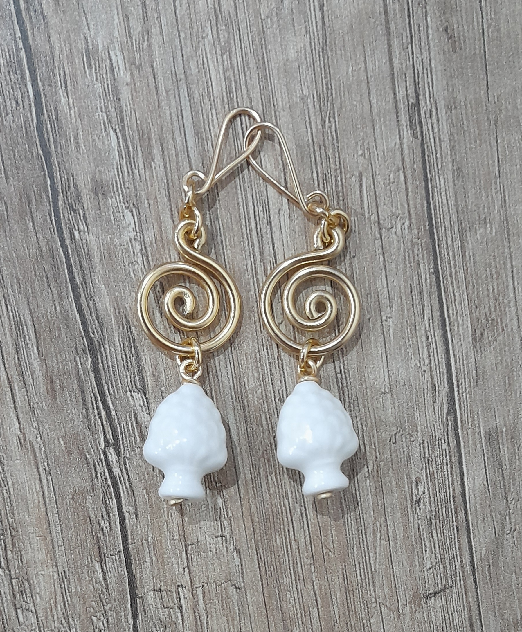 Orecchini artigianali con pigne siciliane bianche in ceramica, fatti a mano con filo d'alluminio anodizzato dorato. Ganci(monachelle) antiallergici, artigianali 100% alluminio senza nichel ne altri metalli.L'alluminio anodizzato è un metallo che non si ossida anche se a contatto con acqua, profumo o detergenti. leggerissimo ed antiallergico.Acquistando questo prodotto non compri un semplice oggetto, ma ore di lavoro, prove e fallimenti, un po' del mio tempo, amore e passione che dedico ad ogni mia creazione.Misura:62x20mm pigna:19x14x12mm Peso:8 grammi - Zanghi collection Orecchini artigianali con pigne siciliane bianche