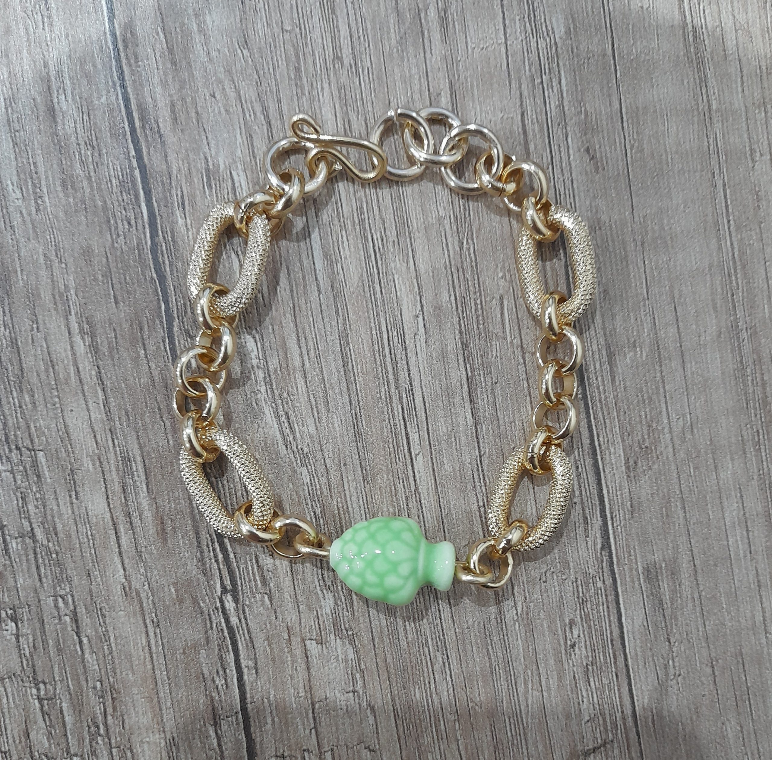 Bracciale artigianale con pigna verde in ceramica fatto a mano con alluminio anodizzato dorato.Nel prodotto la chiusura, è fatta a mano in alluminio perché è un metallo leggerissimo che non fa allergia (100%alluminio) e non si ossida anche se a contatto con acqua, profumo o detergenti.con questo prodotto acquisti un pezzo unico, non stai comprando un semplice oggetto ma un pezzo di cuore, ore di lavoro, prove e fallimenti, amore e passione che dedico ad ogni mia creazione.Misura : regolabile pigna 19x14x12 mm Peso:15 grammi - Zanghi collection Bracciale artigianale con pigna siciliana verde
