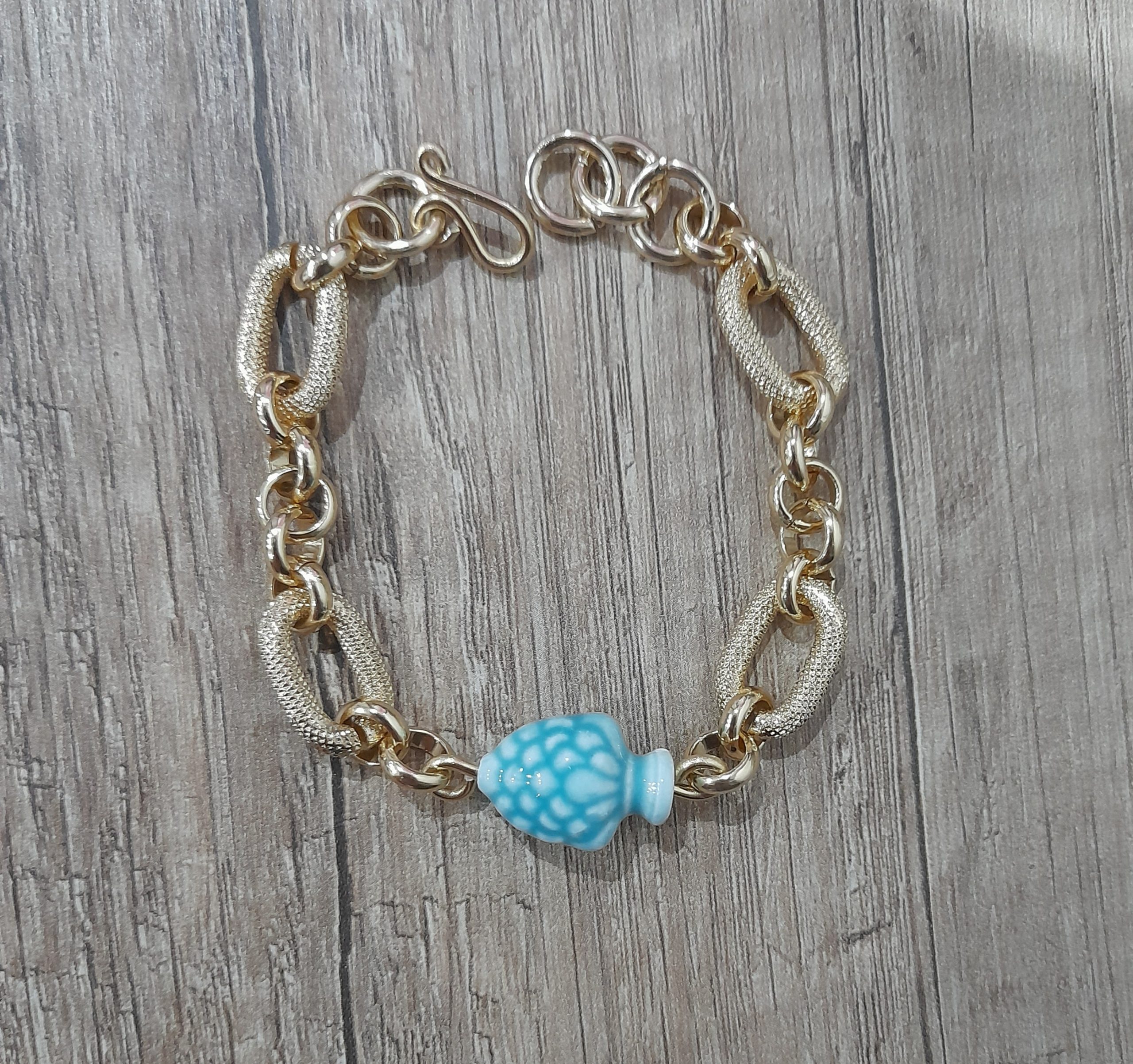 Bracciale artigianale con pigna verde acqua in ceramica fatto a mano con alluminio anodizzato dorato.Nel prodotto la chiusura, è fatta a mano in alluminio perché è un metallo leggerissimo che non fa allergia (100%alluminio) e non si ossida anche se a contatto con acqua, profumo o detergenti.con questo prodotto acquisti un pezzo unico, non stai comprando un semplice oggetto ma un pezzo di cuore, ore di lavoro, prove e fallimenti, amore e passione che dedico ad ogni mia creazione.Misura : regolabile pigna 19x14x12 mm Peso:15 grammi - Zanghi collection Bracciale artigianale con pigna siciliana verde acqua