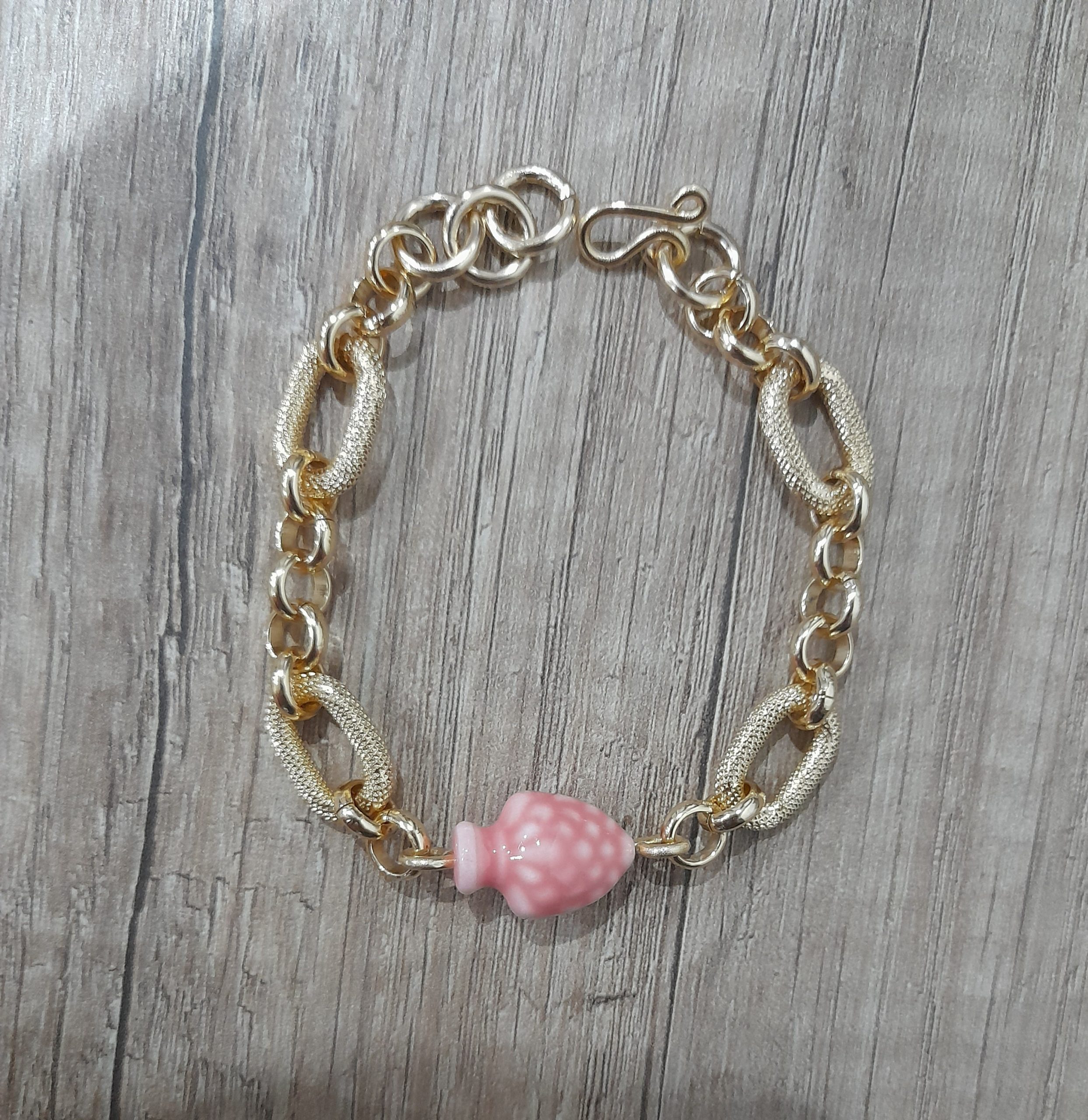 Bracciale artigianale con pigna rosa in ceramica fatto a mano con alluminio anodizzato dorato.Nel prodotto la chiusura, è fatta a mano in alluminio perché è un metallo leggerissimo che non fa allergia (100%alluminio) e non si ossida anche se a contatto con acqua, profumo o detergenti.con questo prodotto acquisti un pezzo unico, non stai comprando un semplice oggetto ma un pezzo di cuore, ore di lavoro, prove e fallimenti, amore e passione che dedico ad ogni mia creazione.Misura : regolabile pigna 19x14x12 mm Peso:15 grammi - Zanghi collection Bracciale artigianale con pigna siciliana rosa