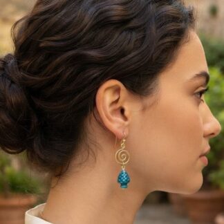 Side profile of a woman wearing a gold spiral drop earring with a blue bead.