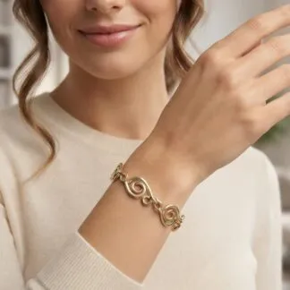 Close-up of a gold swirled-link bracelet on a woman's wrist, wearing a beige sweater.