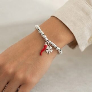 Close-up of a silver beaded bracelet on a wrist, featuring a red chili pepper charm and a silver four-leaf clover charm.