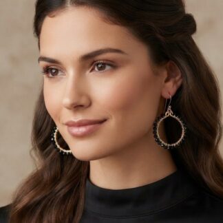 Close-up of a smiling woman with long brown hair wearing large circular hoop earrings with black beads.