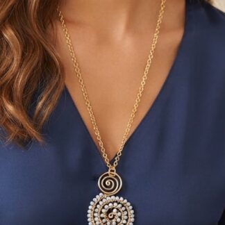 Gold chain necklace with a spiral and bead-adorned circular pendant resting on a navy blouse.