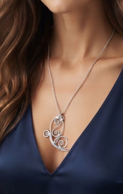 1790768941514 - Zanghi collection Silver pendant necklace with an intricate swirling design on a navy V-neck dress.