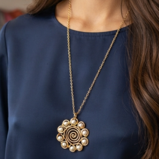 Gold spiral pendant necklace with pearl accents resting on a navy blouse, seen on a person